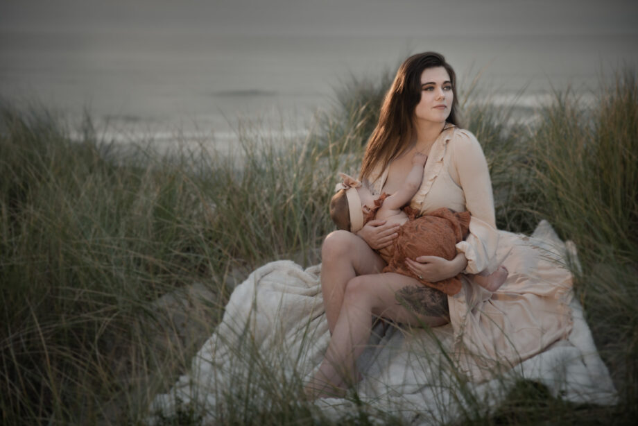 img="motherhood; mother nursing infant on the beach Southern Oregon photography by Eric Wyatt"